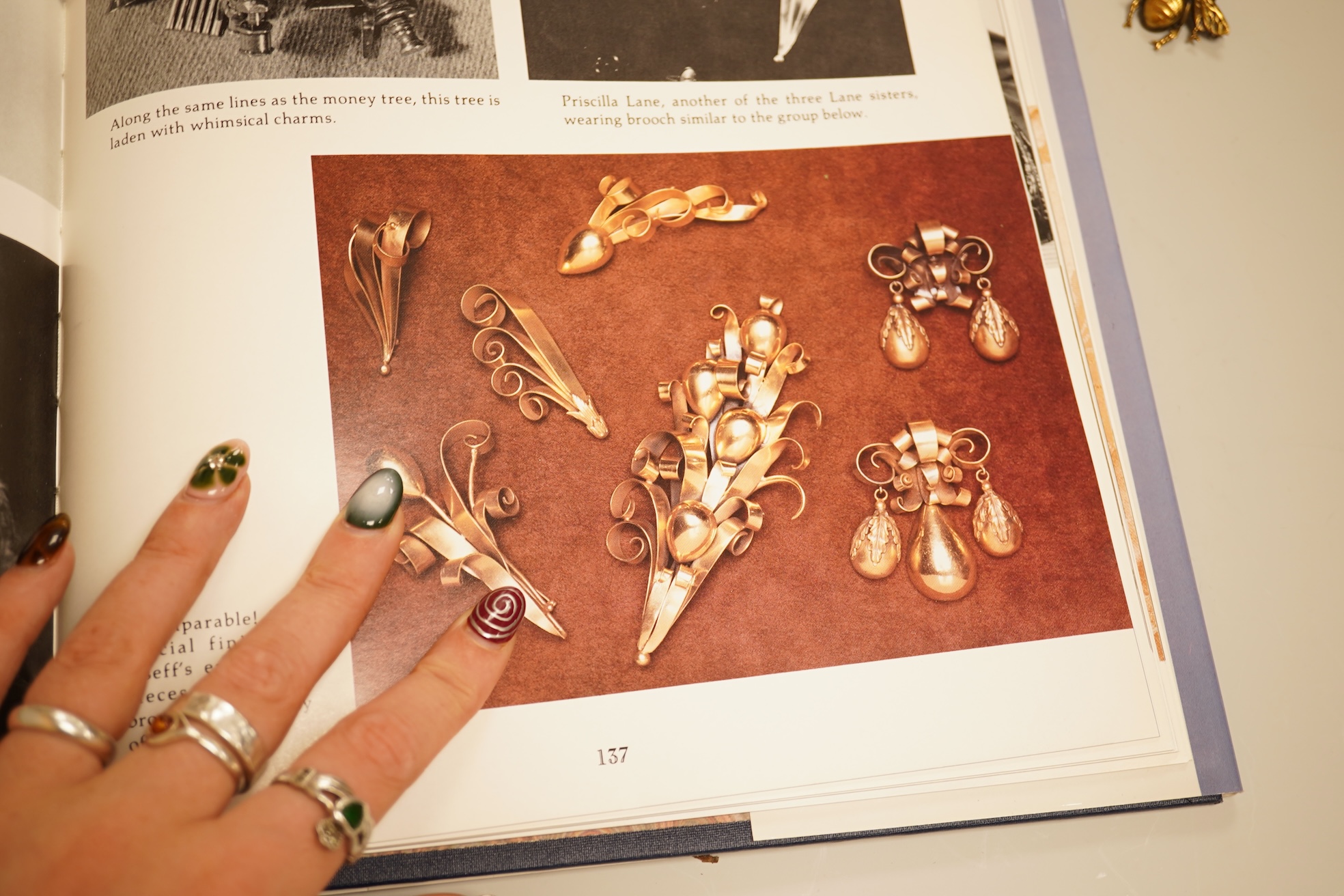 A mid 20th century North American gilt metal bee brooch by Joseff, wing span 30mm, together with a hard back copy of 'Jewelry of the Stars, Creations from Joseff of Hollywood' by Joanne Dubbs Ball.